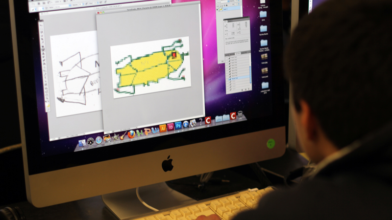 A student adds color to orignal artwork for his video game.