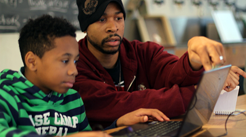 An artist-teacher consults with a student on his video game.